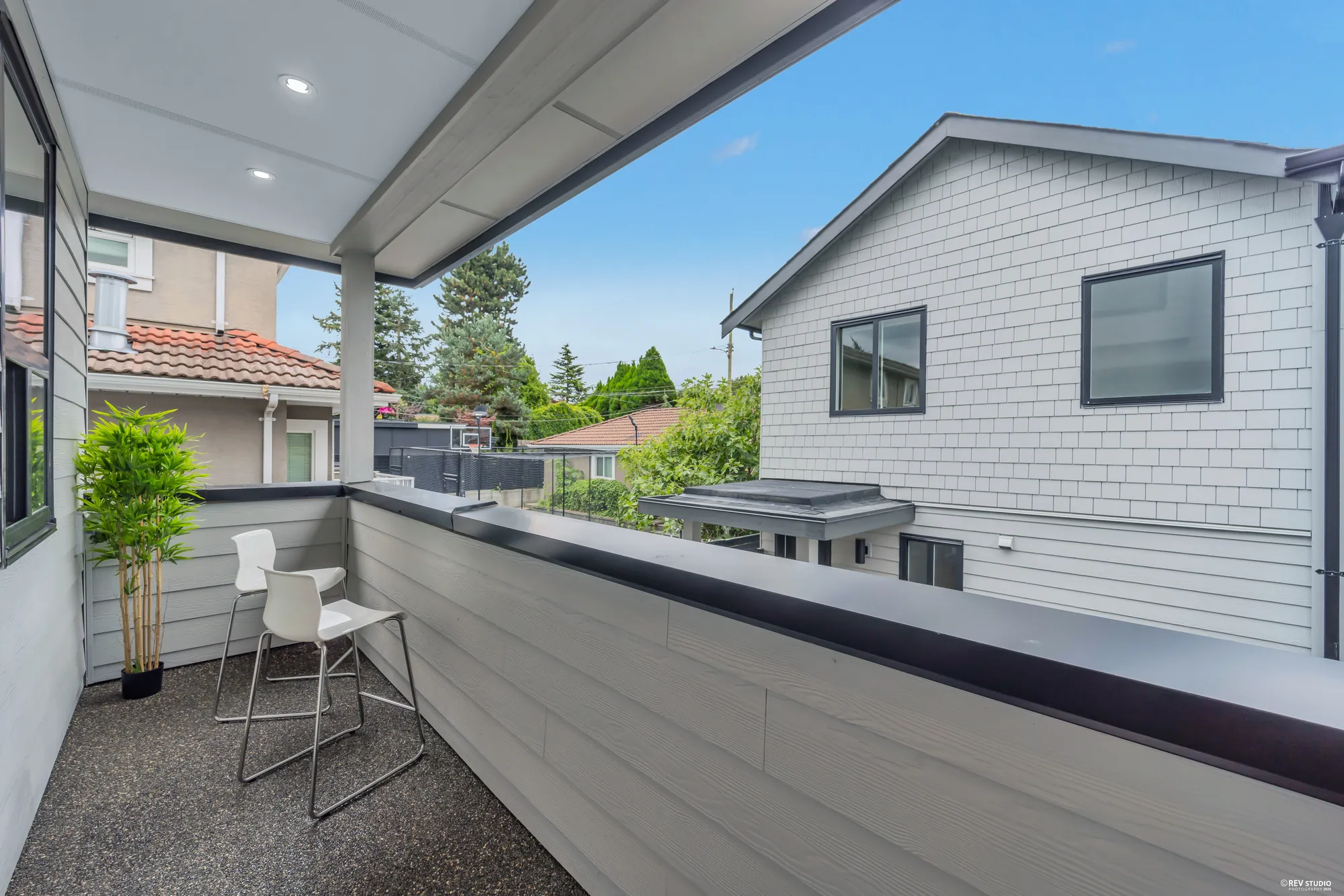 The back balcony with a planter and seating, facing the rear building across the lot