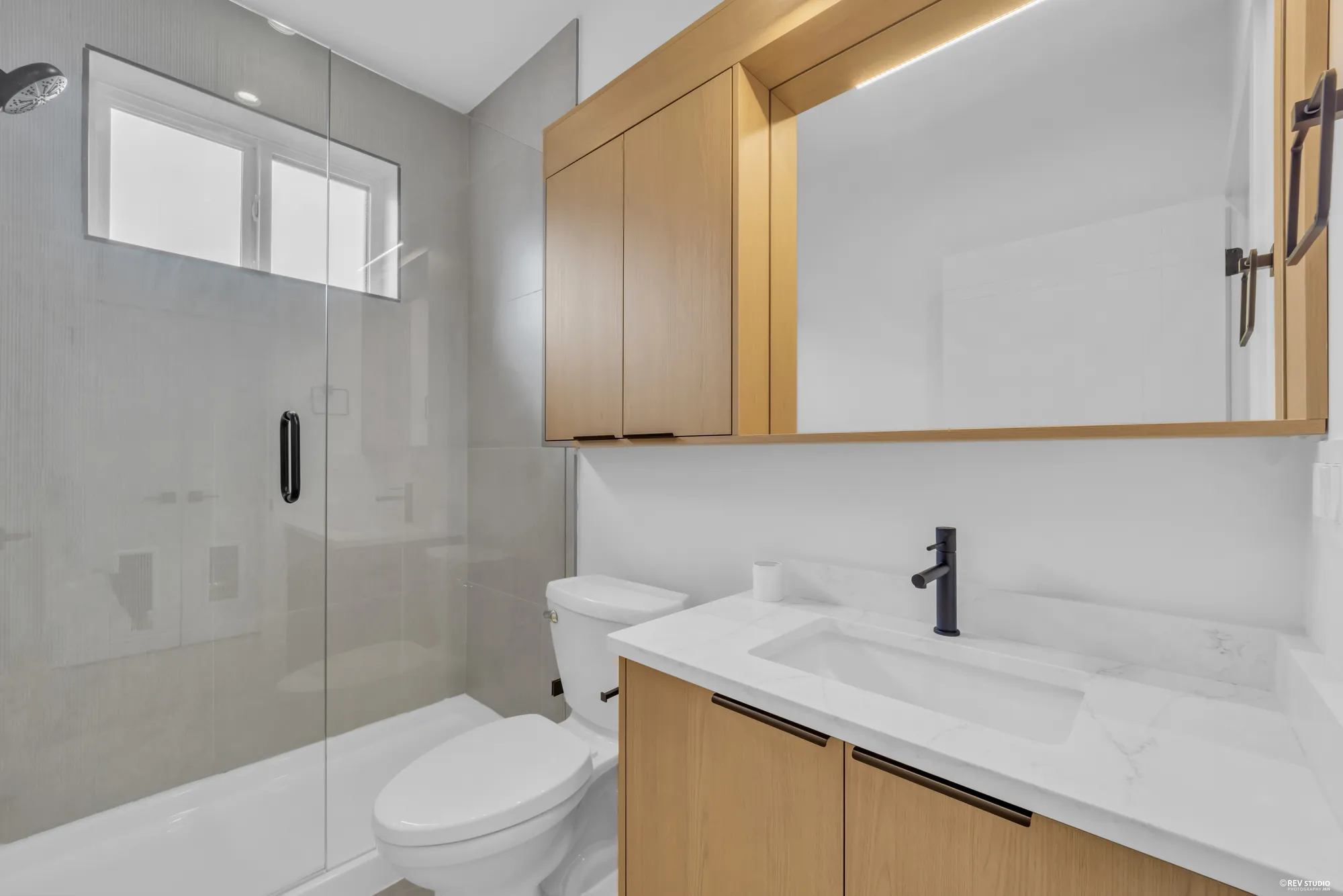 Bathroom with a glass shower, stone-topped vanity and a timber mirror cabinet