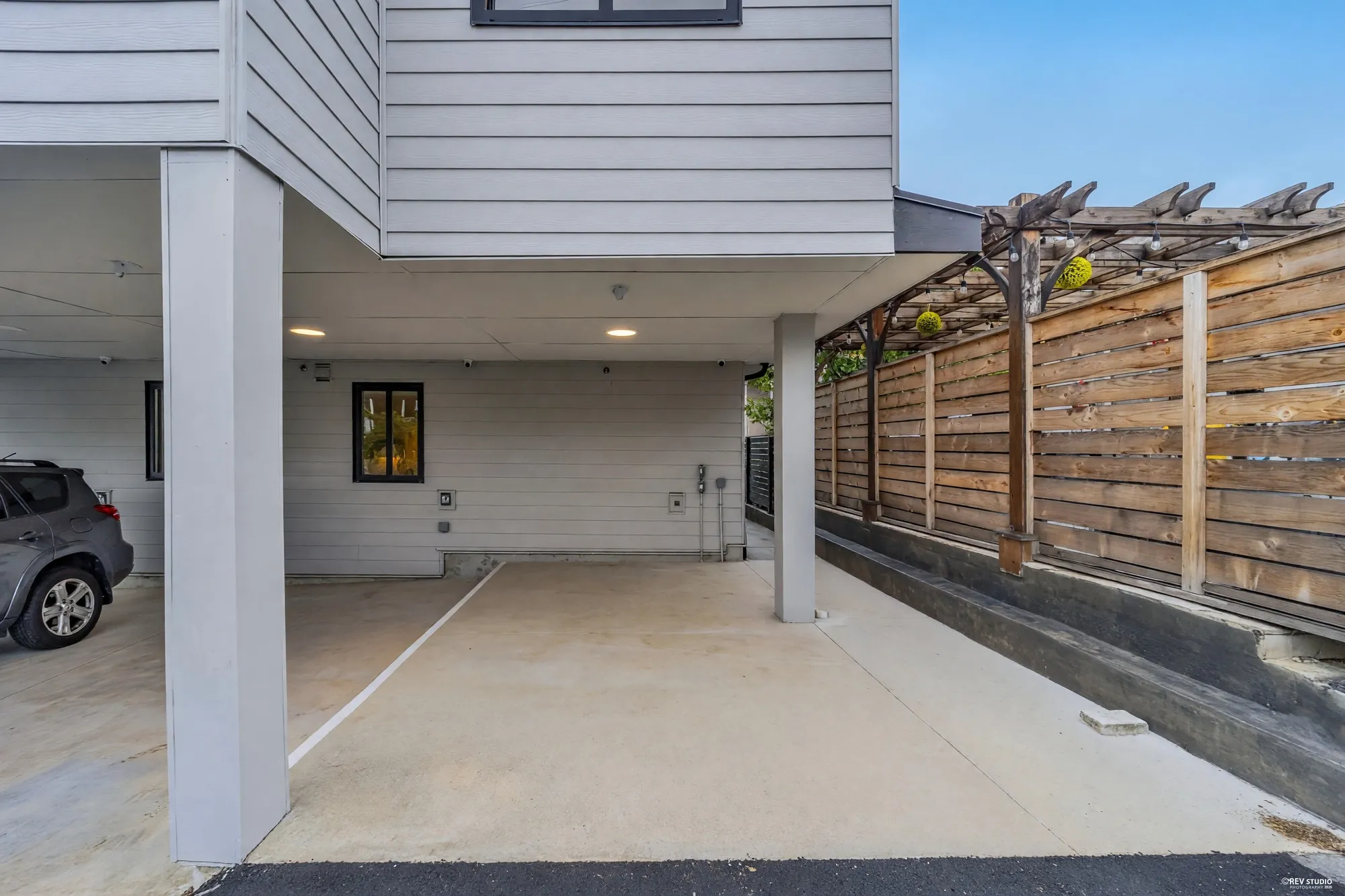 Covered carport with a parked car and a walkway leading through