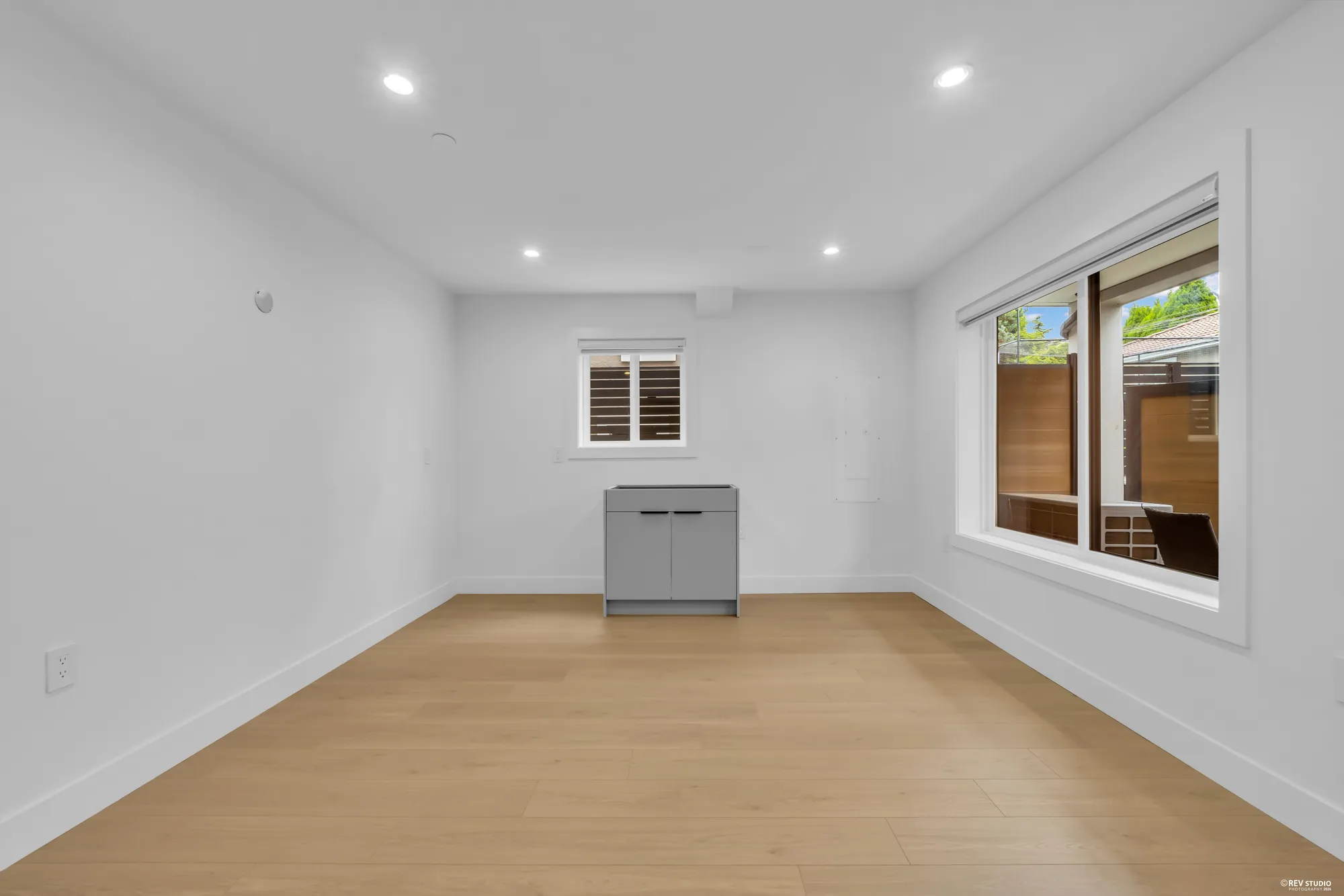 Unfurnished family room with a low cabinet, a window and a door to the patio