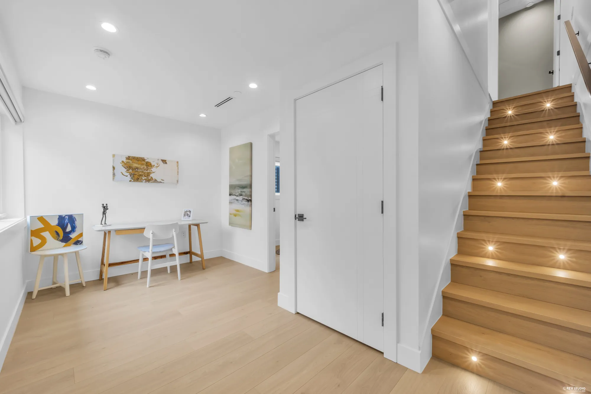 Entry foyer with a timber stair lit at each tread and a door to the side