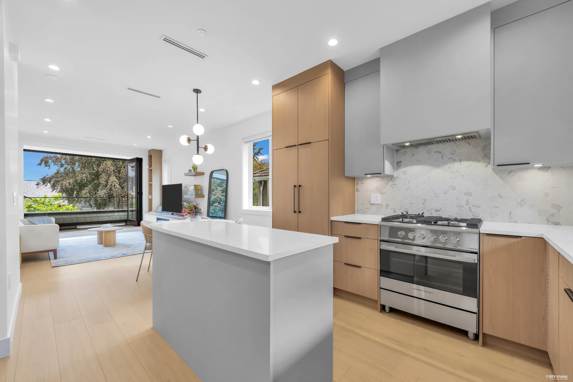 Kitchen with a quartz island, stainless range and hood, and a view through to the living room