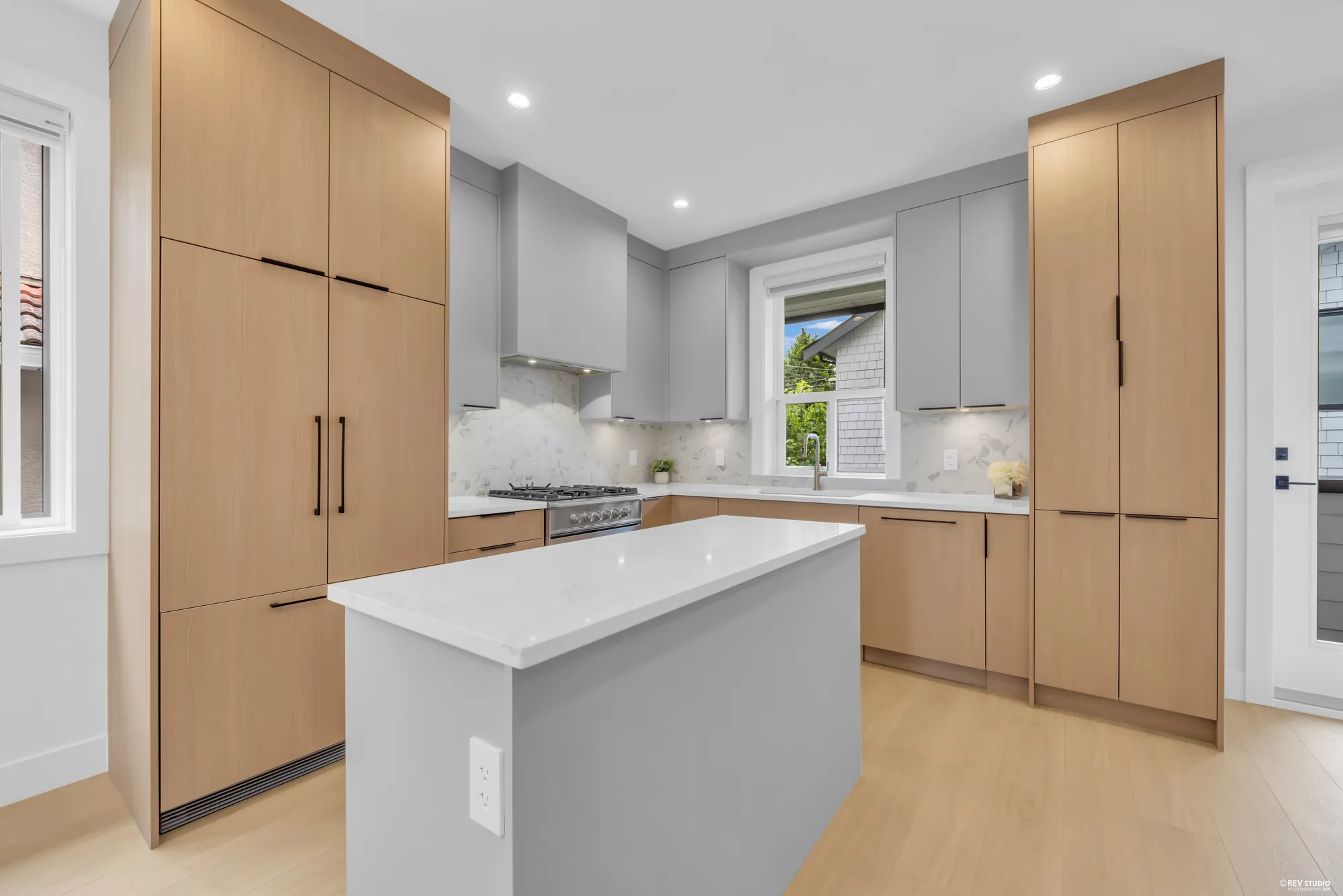 Full-height pale timber cabinetry along the back wall of the kitchen