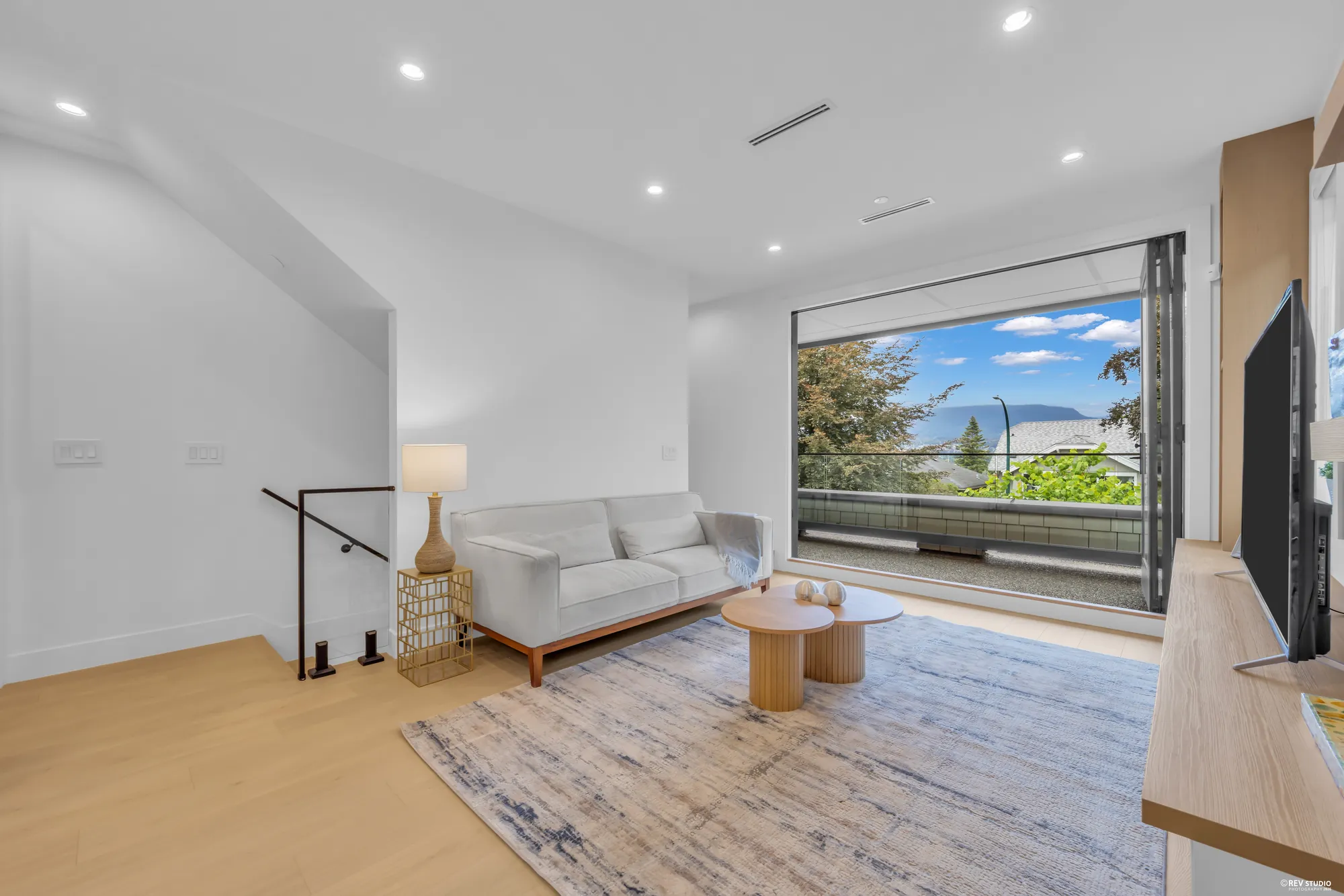 Living room seen from the stair, with a sofa and the balcony beyond