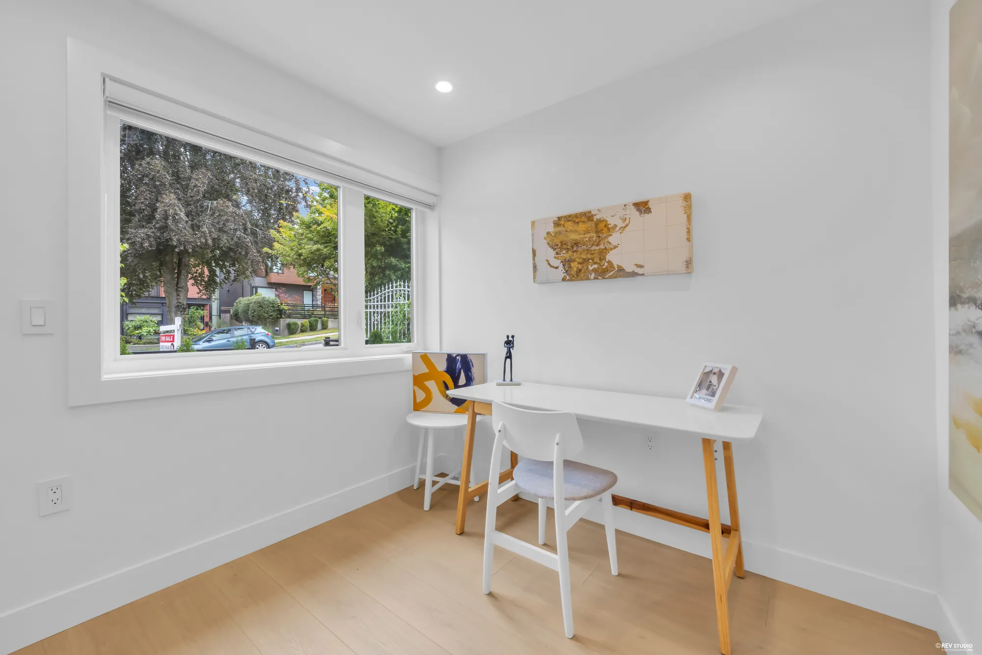 Small office with a narrow white desk and stool beside a window