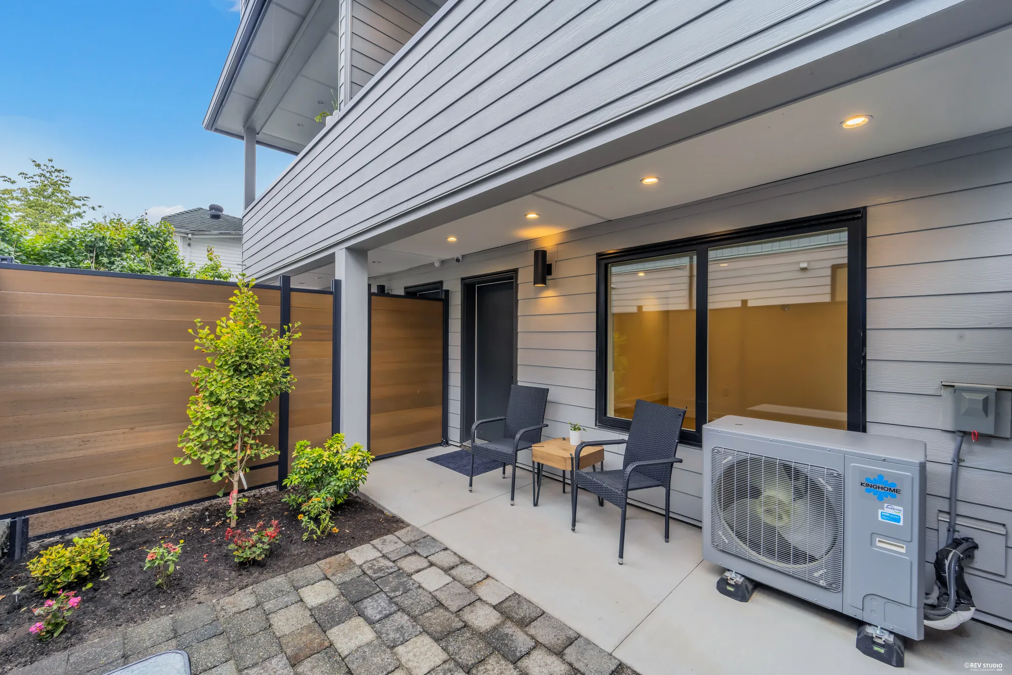Paved patio with two chairs and a small table against a timber fence