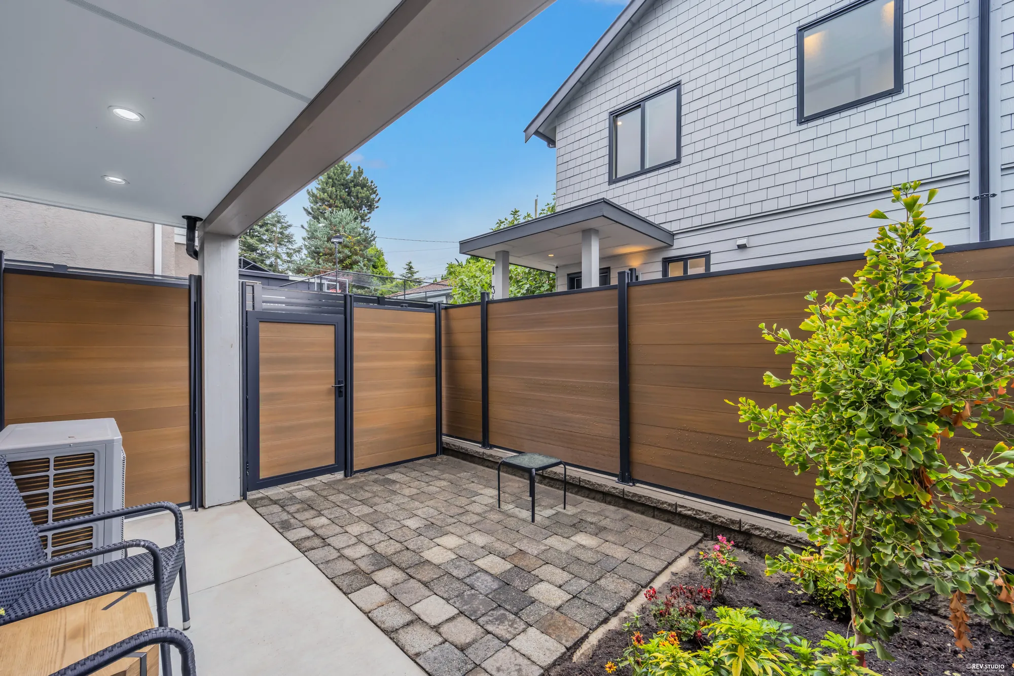The patio looking toward a gate in the timber fence, with young planting