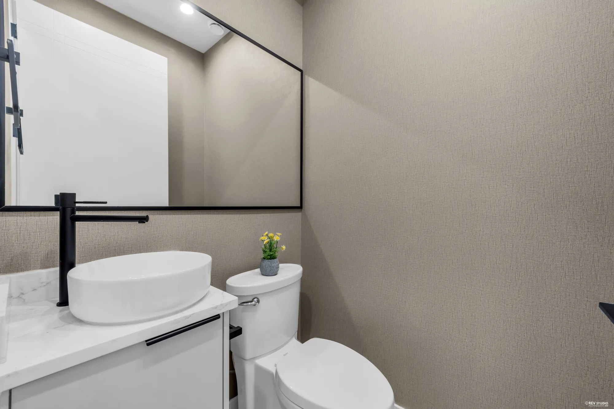 Powder room with a vessel basin on a stone counter and a black tap