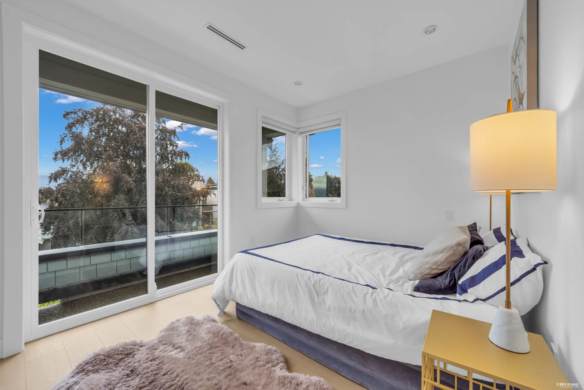 Primary bedroom with a made bed, bedside lamps and sliding doors onto a balcony